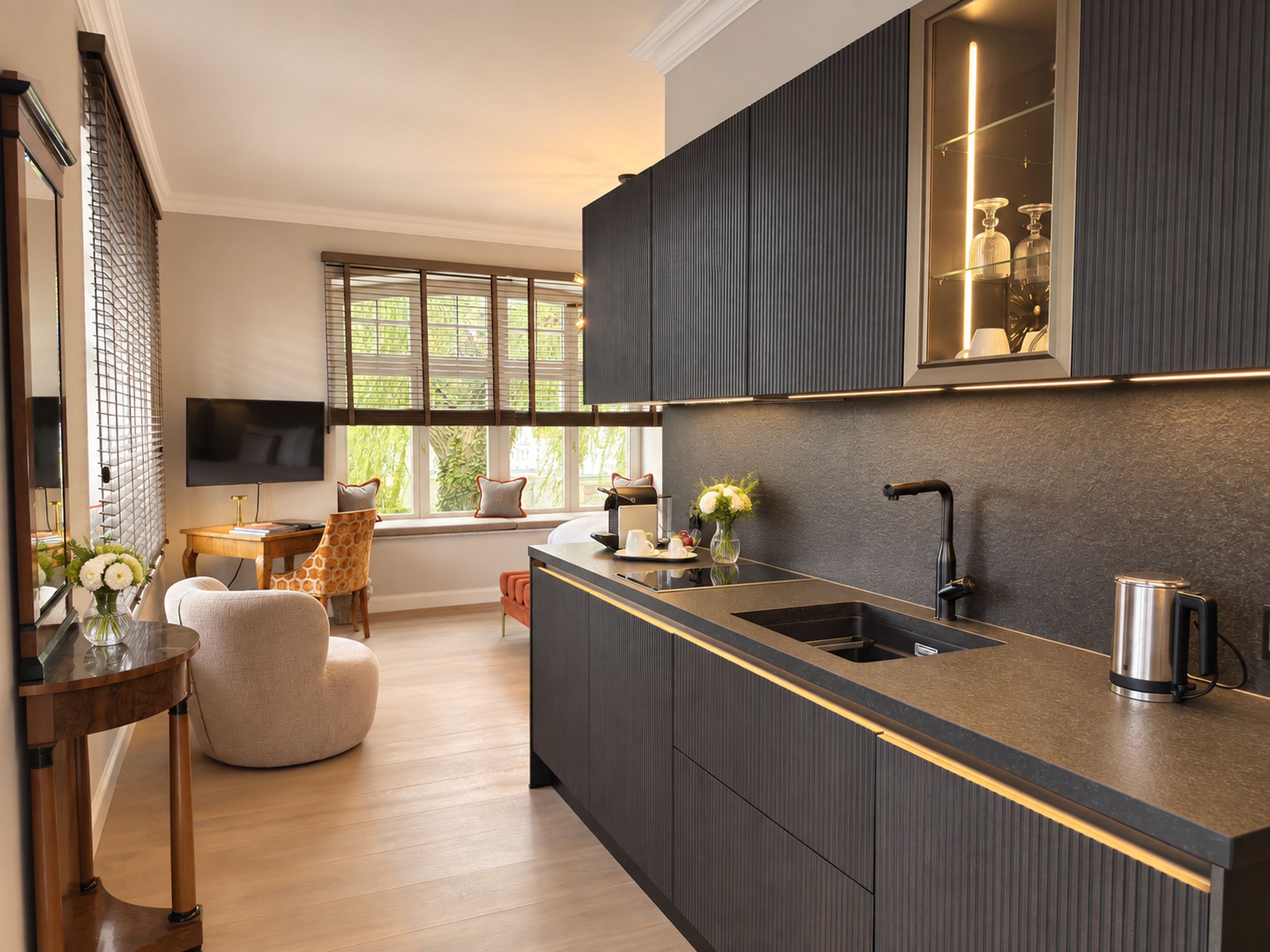 Una cocina moderna con una isla integrada, muebles oscuros y un amplio ventanal que proporciona luz natural.