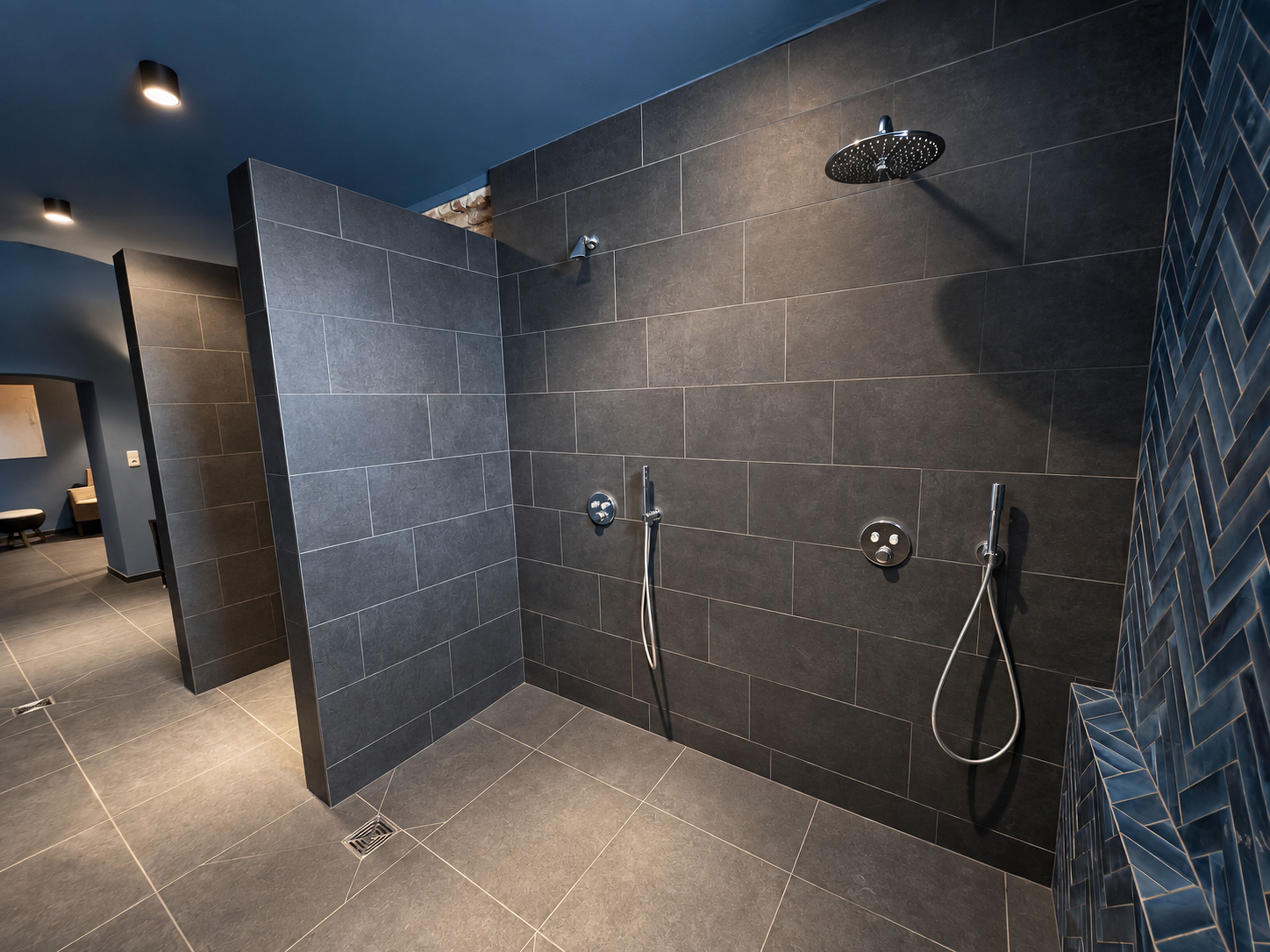 A modern bathroom with dark tiles, a shower area, and a visible vent.