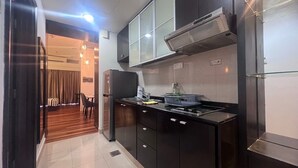 A modern kitchen with dark cabinetry, a stainless steel refrigerator, and a built-in stove. - Pyramid Spacious Lovely Couple Suites双威城公寓式套房 (Petaling Jaya)