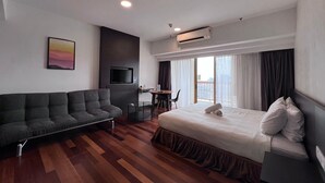 A modern hotel room with a sofa, a bed, a TV, a desk, and a large window with curtains. - Pyramid Spacious Lovely Couple Suites双威城公寓式套房 (Petaling Jaya)
