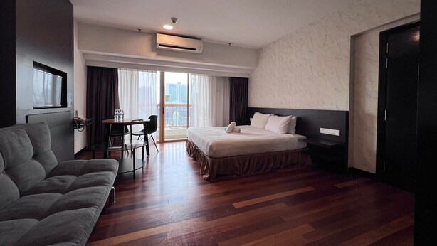 A hotel room with a bed, a sofa, a desk, and a view of the city. - Pyramid Spacious Lovely Couple Suites双威城公寓式套房 (Petaling Jaya)