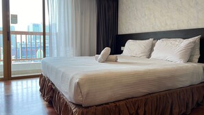 A hotel room with a large bed, a view of the city through a balcony, and a marble-patterned wall. - Pyramid Spacious Lovely Couple Suites双威城公寓式套房 (Petaling Jaya)