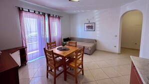 Un espace repas comprenant une table et des chaises en bois, un canapé et un luminaire suspendu au plafond.