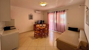 Une pièce de taille modeste comprenant une table à manger, des chaises, un lit, un téléviseur et un coin cuisine.