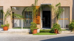 A building with multiple balconies, potted plants, and a wooden door with the number 4. - Rosemont Studio With Balcony in Larnaca (Larnaca)