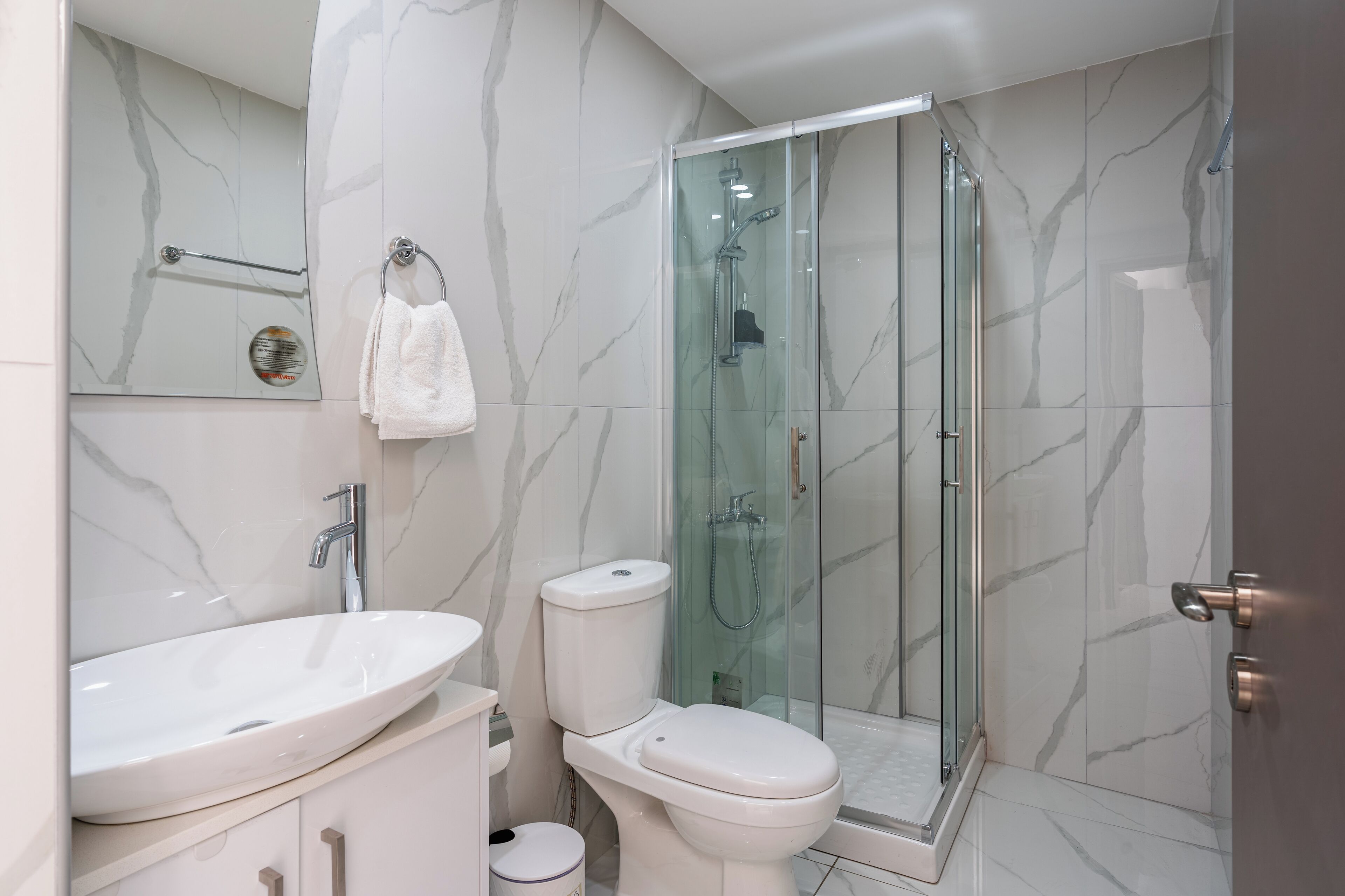 Une salle de bain moderne avec une douche à parois de verre, un lavabo blanc et des toilettes.