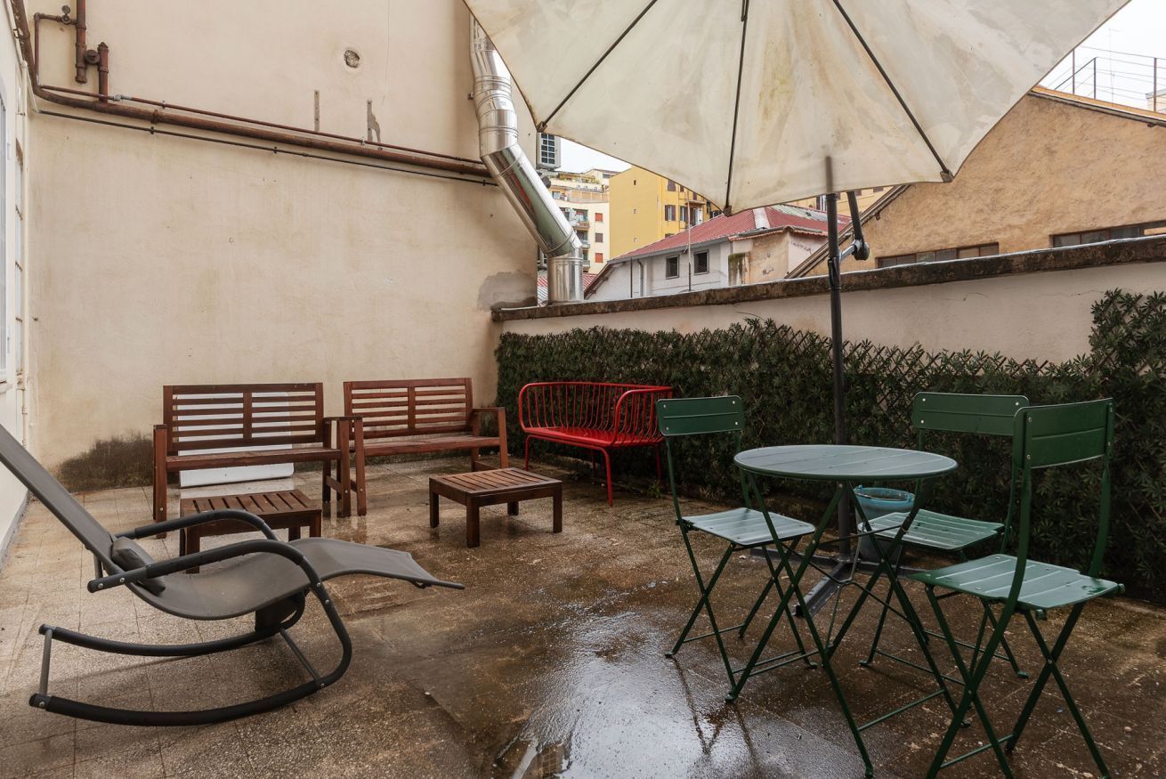 An outdoor patio with a table and chairs, a bench, and a rocking chair.