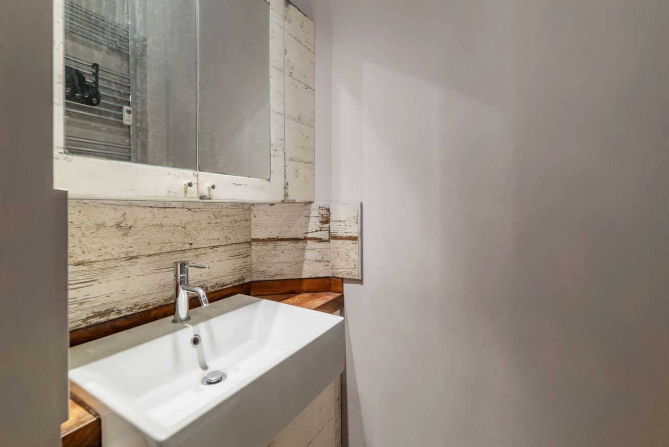 Ein Badezimmer mit einem weißen Waschbecken, einer Holzvertäfelung und einem Fenster.