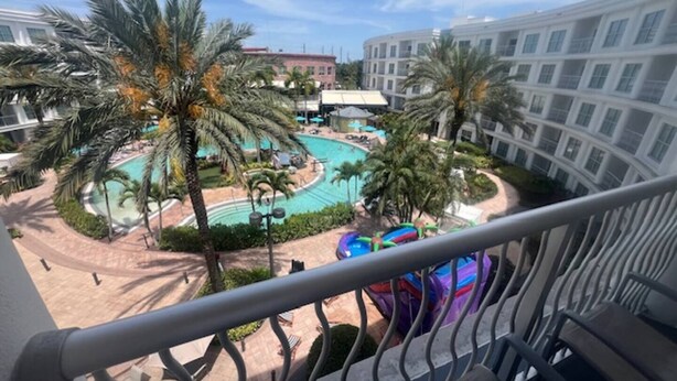 A hotel with a pool area, palm trees, and a water slide.