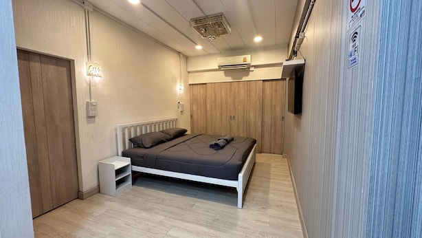 A bedroom with a bed, bedside table, and a wall-mounted TV. - Far Far Away Hostel Chiangmai (Chiang Mai)