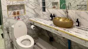 A bathroom with a marble floor, a white toilet, a gold sink, and a large mirror. - Far Far Away Hostel Chiangmai (Chiang Mai)