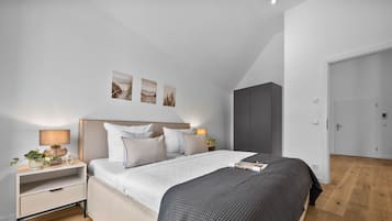 Un dormitorio moderno con una cama grande, mesitas de noche, un armario y cuadros en la pared.