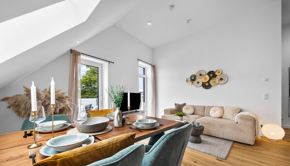 A modern loft with a dining area, a living room, and a large window.