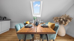 Un comedor con una mesa de madera, dos sillas y un jarrón de flores secas.