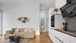 Una sala moderna con un sofá color beige, una mesita de centro y un elemento decorativo en la pared.