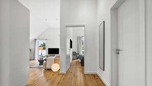 Un interior moderno y bien iluminado, con piso de madera, un sofá, un televisor y un área de comedor con una mesa y sillas.