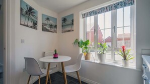 A dining area with a round table, two chairs, and three potted plants. - Stylish 3-Bed Retreat with Garden and Parking (Woodford Halse)