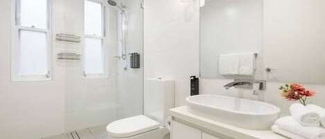 A modern bathroom with a shower, toilet, sink, and a large mirror.