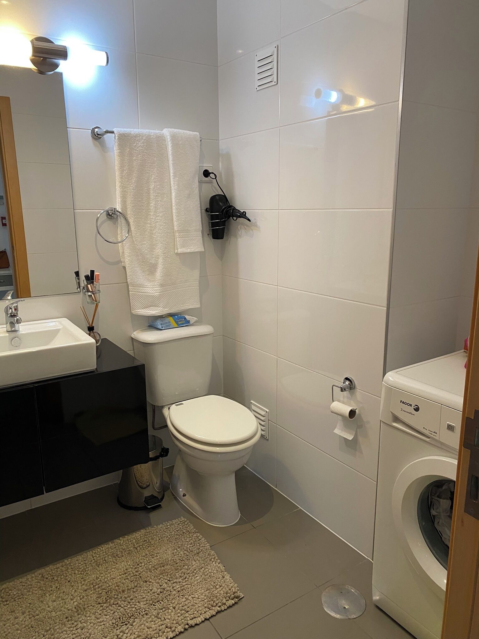 A modern bathroom with a toilet, sink, and washing machine.