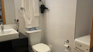 Et moderne badeværelse med toilet, vask og vaskemaskine.