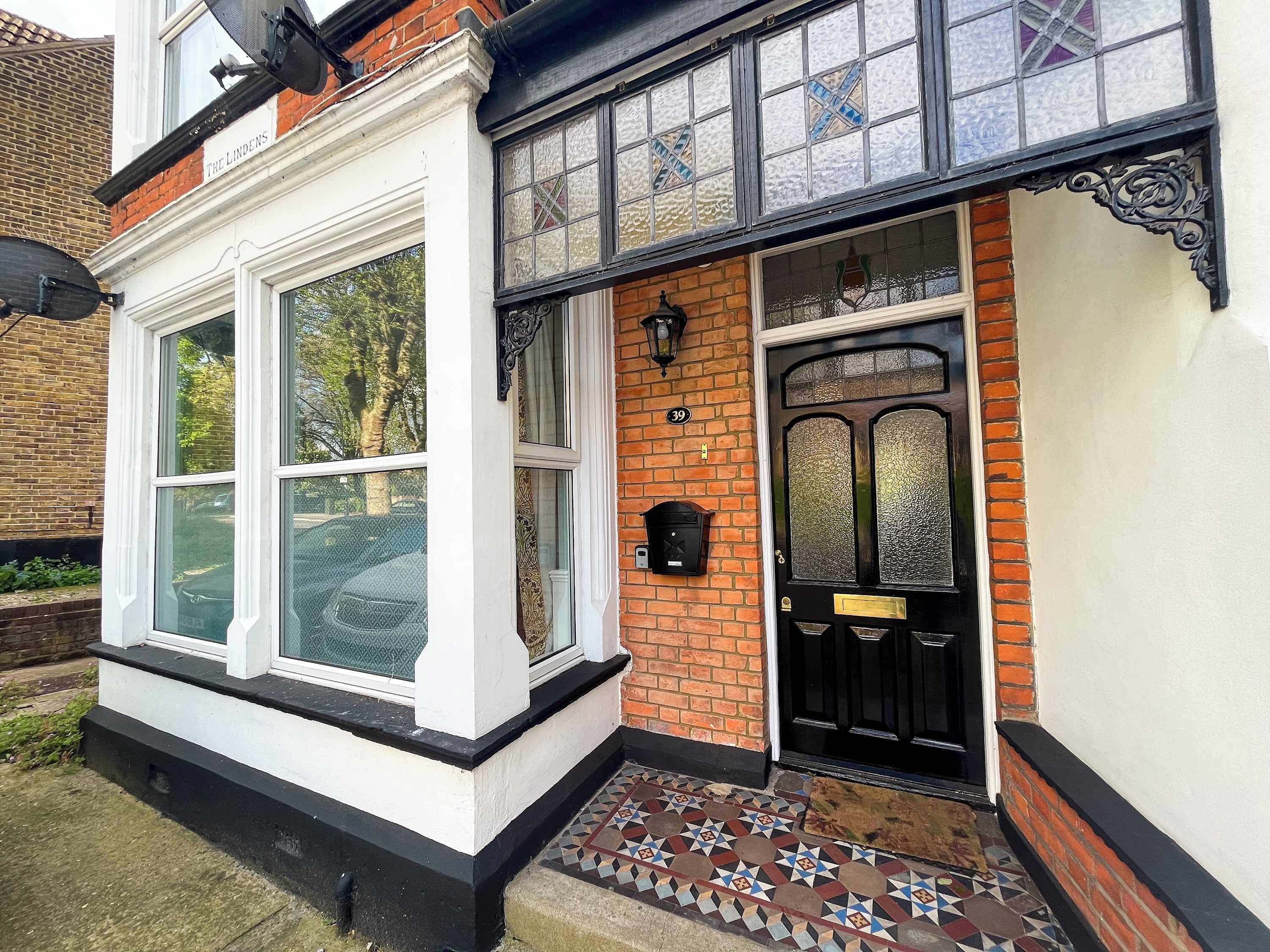 A traditional building with a black door, a white-framed window, and a tiled entrance.