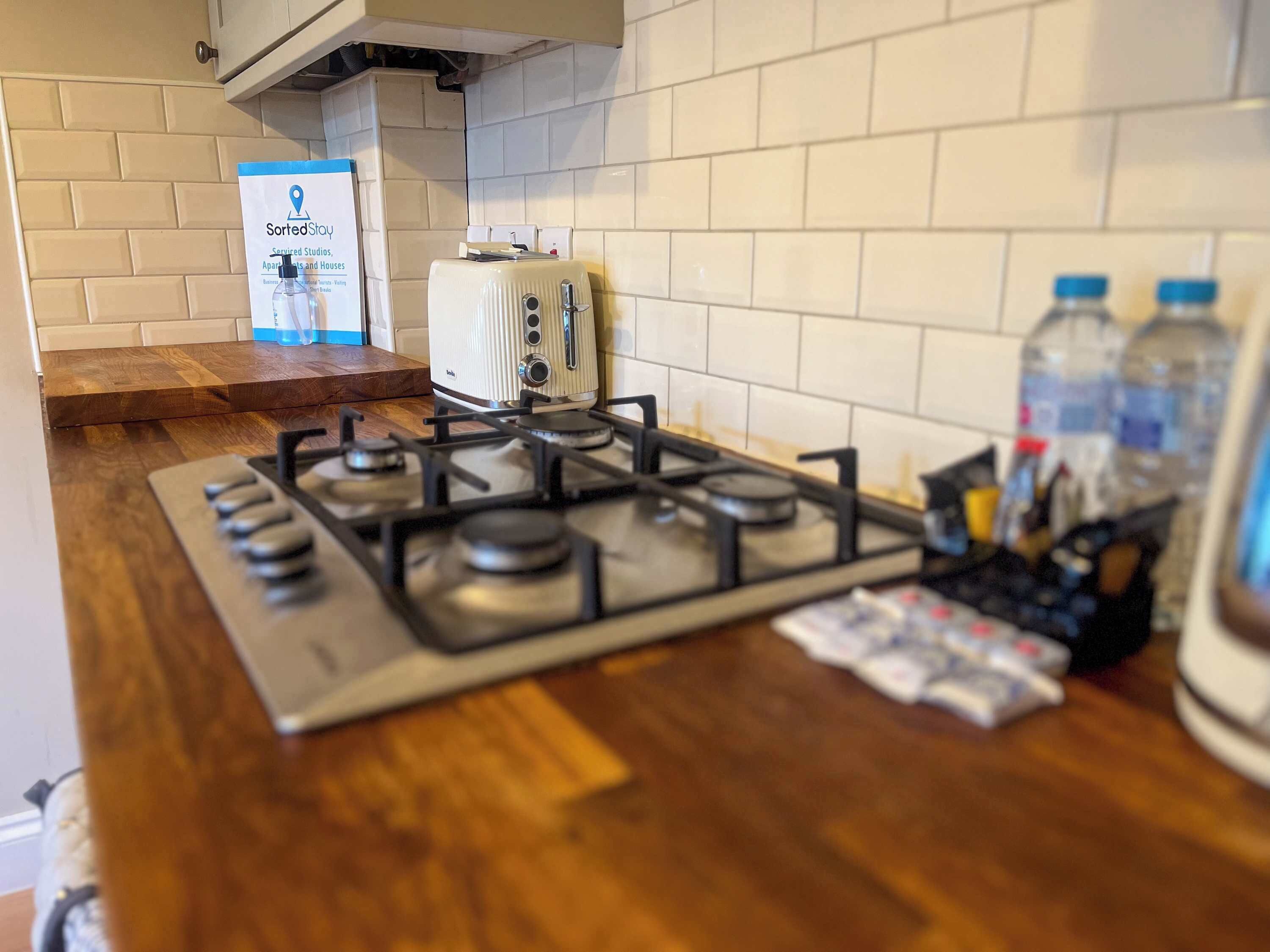 A kitchen with a gas stove, a toaster, and a water dispenser.