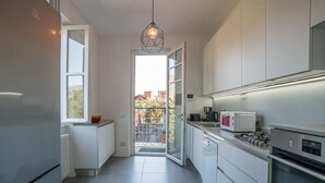 A modern kitchen with a refrigerator, microwave, stove, and a hanging light fixture.