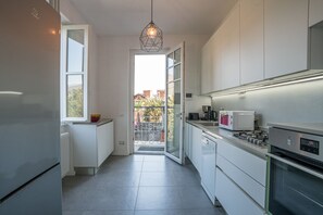 A modern kitchen with a refrigerator, microwave, stove, and a hanging light fixture.