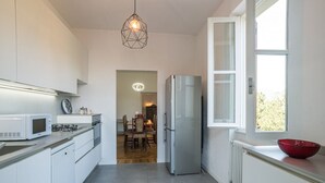 A modern kitchen with white cabinets, a stainless steel refrigerator, a microwave, and a red bowl on the counter.