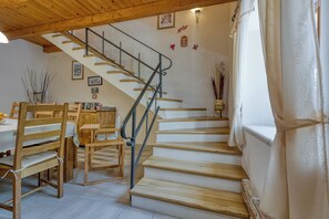 Una escalera de madera con barandillas metálicas, que conduce a una zona de descanso con una mesa y sillas.