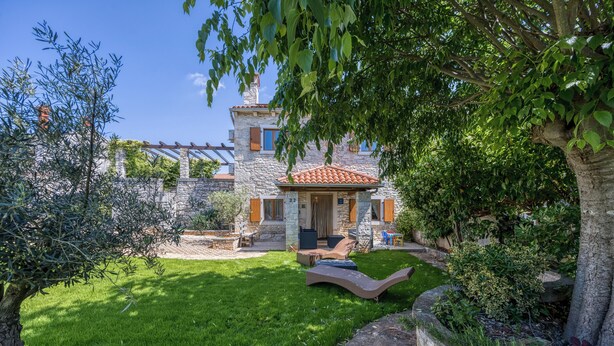 A stone house with a tiled roof, a grassy yard, and a wooden deck with seating. - Casa Rustica Felker With Private Pool (Marcana)