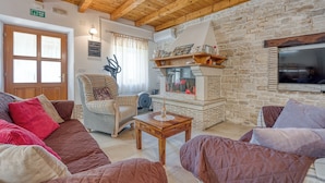 A cozy living room with a stone fireplace, wooden ceiling beams, and a comfortable seating area. - Casa Rustica Felker With Private Pool (Marcana)