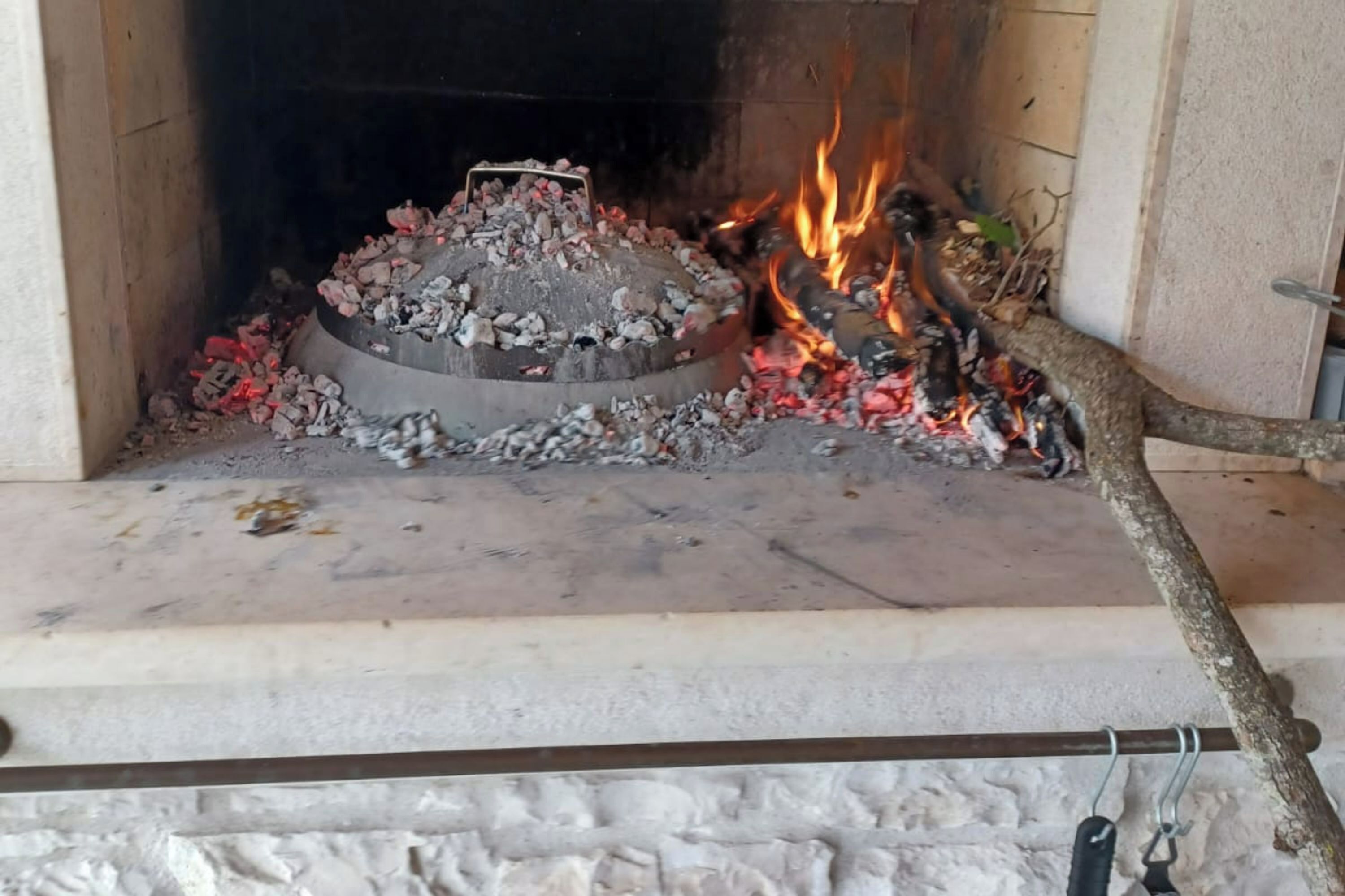 Une cheminée avec des bûches qui brûlent et un foyer en métal.
