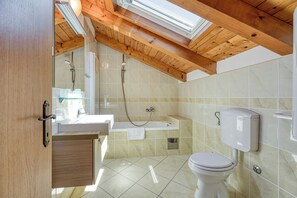Ein modernes Badezimmer mit Dachfenster, Badewanne, Toilette und Waschtisch.