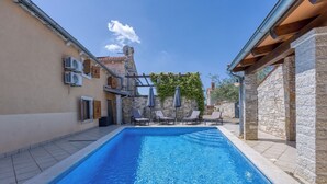 A swimming pool with lounge chairs and umbrellas, surrounded by stone walls and a clear blue sky. - Casa Rustica Felker With Private Pool (Marcana)