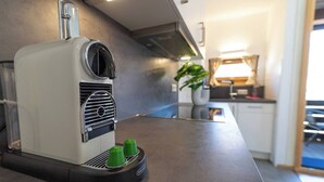 Een moderne keuken met een ingebouwde koffiezetapparaat, een plant en een schoon aanrecht.