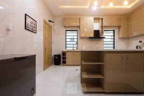 A modern kitchen with marble flooring, wooden cabinets, and a built-in oven. - Javes Luxury Residences (Lagos)