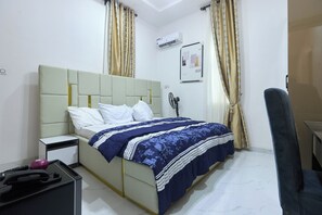Une chambre d’hôtel équipée d’un lit, d’une table de chevet, d’un bureau et d’un appareil de climatisation.