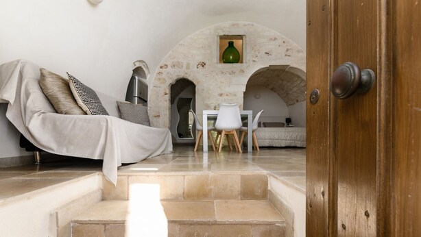 Una sala de estar acogedora con un sofá, una mesita de centro y un arco de piedra.