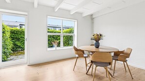 Un comedor con una mesa redonda, seis sillas y un jarrón con flores.