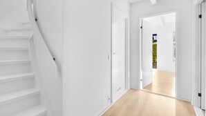 Un interior moderno con paredes blancas, piso de madera y una escalera.
