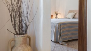 A hallway leading to a bedroom with a bed, a vase with branches, and a tiled floor. - Villetta Sulvia - Alloggio Alaterno con Terrazza Vista Mare (Corsano)