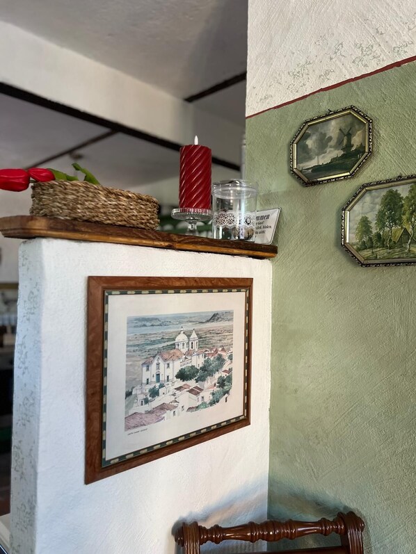 Une photo encadrée représentant une ville côtière, une bougie rouge et deux décorations murales hexagonales.