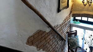 Un escalier avec une rampe en bois, un mur en briques et un tableau encadré accroché au mur.