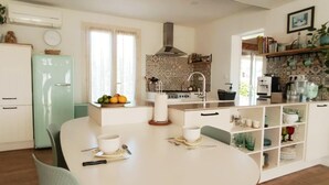 Una cocina compacta con refrigerador, una mesa de comedor con sillas y un lavamanos.