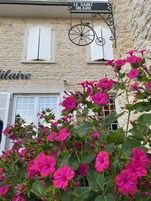 A stone building with a sign reading "LE SAINT HILAIRE" and a bicycle hanging from the sign.