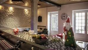 A kitchen with a checkered countertop, a fruit basket, a Christmas tree, and a clock on the wall.