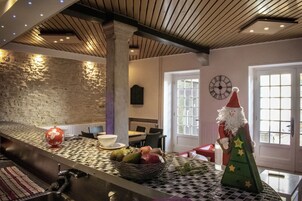 Uma cozinha com bancada xadrez, cesta de frutas, árvore de Natal e um relógio na parede.