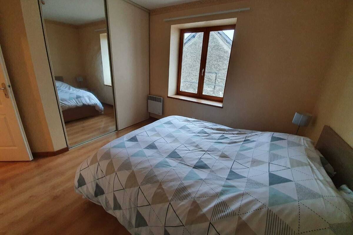A bedroom with a bed, a window, and a mirror.