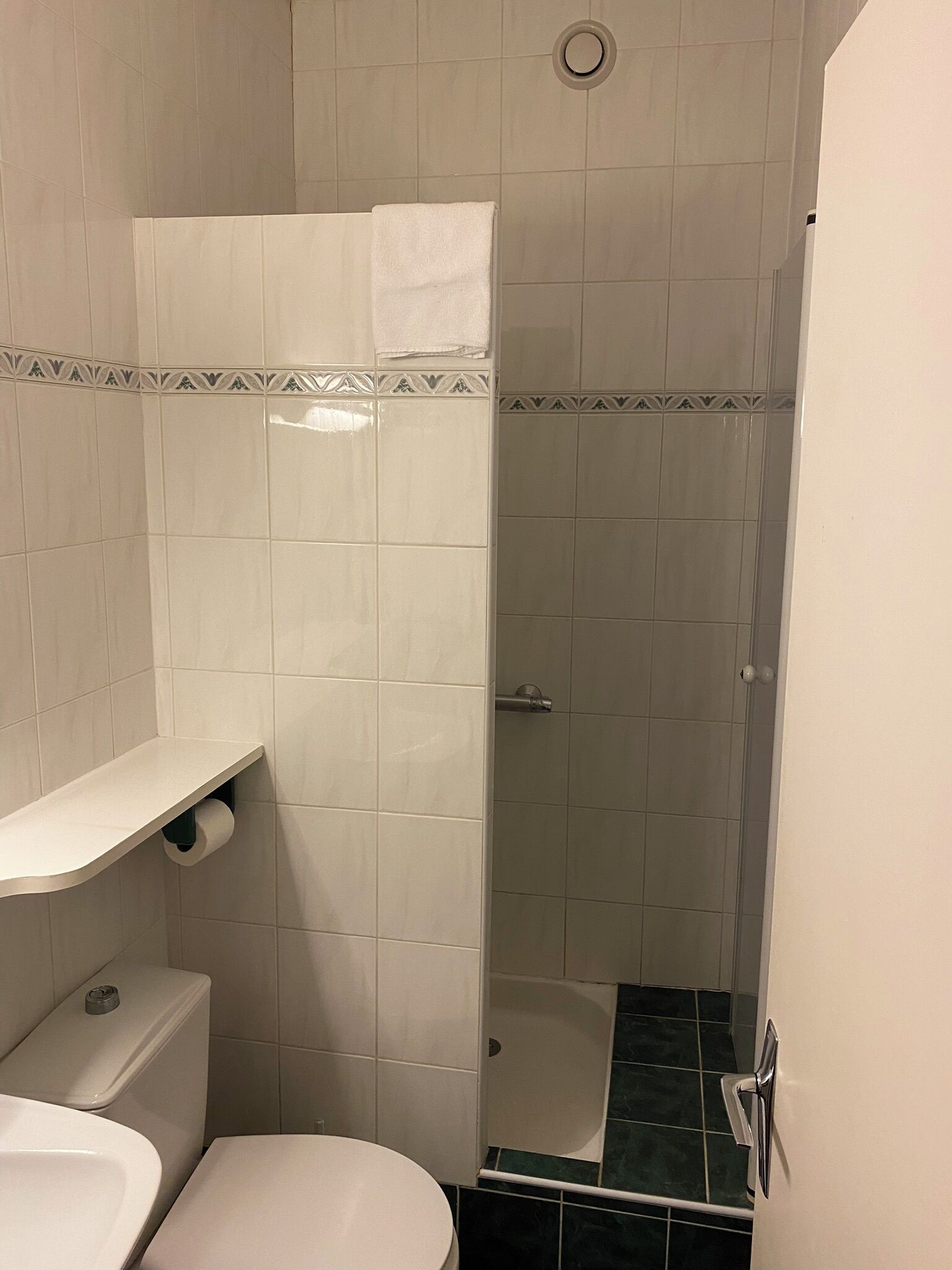A bathroom with a toilet, sink, shower, and a towel rack.